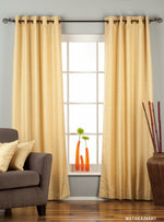 Golden raw silk grommet top curtains hung at a window