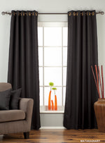 Black raw silk grommet top curtains hung at a window