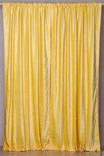 Yellow velvet rod pocket curtains hung at a window