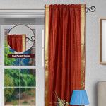 Rust sari rod pocket curtains hung at a window
