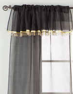 Black sheer tissue rod pocket curtains hung at a window