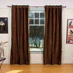 Brown velvet grommet top curtains hung at a window