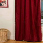 Burgundy velvet rod pocket curtains hung at a window