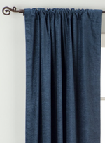 Navy blue velvet rod pocket curtains hung at a window