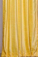 Yellow velvet rod pocket curtains hung at a window