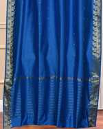 Blue sari grommet top curtains hung at a window