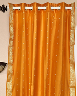 Mustard sari grommet top curtains hung at a window