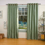 Olive green velvet grommet top curtains hung at a window