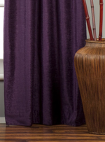 Purple velvet grommet top curtains hung at a window