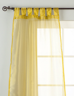 Gold sheer tissue tab top curtains hung at a window