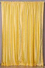 Yellow velvet rod pocket curtains hung at a window