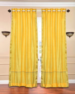 Yellow sari grommet top curtains hung at a window