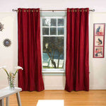 Burgundy velvet grommet top curtains hung at a window