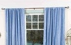 Caribbean blue velvet rod pocket curtains hung at a window