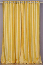 Yellow velvet grommet top curtains hung at a window