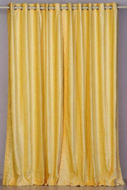 Yellow velvet grommet top curtains hung at a window