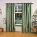Olive green velvet grommet top curtains hung at a window
