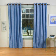 Light blue velvet grommet top curtains hung at a window