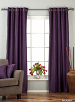 Purple velvet grommet top curtains hung at a window