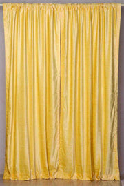 Yellow velvet rod pocket curtains hung at a window