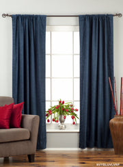 Navy blue velvet rod pocket curtains hung at a window