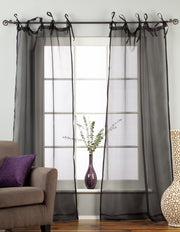Black sheer tissue tie top curtains hung at a window