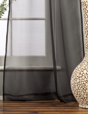 Black sheer tissue tie top curtains hung at a window
