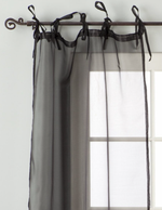 Black sheer tissue tie top curtains hung at a window