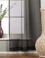 Black sheer tissue rod pocket curtains hung at a window