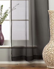 Black sheer tissue rod pocket curtains hung at a window