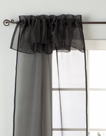 Black sheer tissue rod pocket curtains hung at a window