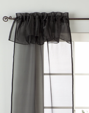 Black sheer tissue rod pocket curtains hung at a window