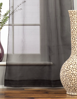 Black sheer tissue rod pocket curtains hung at a window