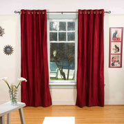 Burgundy velvet grommet top curtains hung at a window