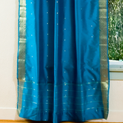 Turquoise sari rod pocket curtains hung at a window