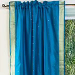 Turquoise sari rod pocket curtains hung at a window
