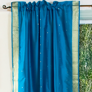 Turquoise sari rod pocket curtains hung at a window