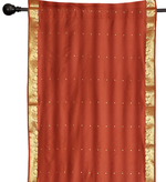 Rust sari rod pocket curtains hung at a window