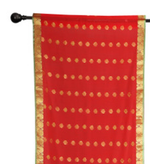 Red sari rod pocket curtains hung at a window