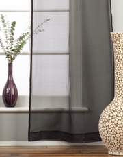 Black sheer tissue rod pocket curtains hung at a window