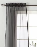 Black sheer tissue rod pocket curtains hung at a window