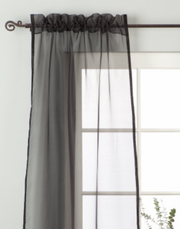 Black sheer tissue rod pocket curtains hung at a window