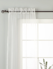 White sheer tissue rod pocket curtains hung at a window