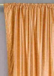 Peach velvet rod pocket curtains hung at a window
