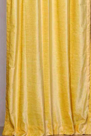 Yellow velvet rod pocket curtains hung at a window