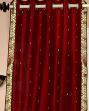 Maroon sari grommet top curtains hung at a window