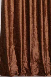 Brown velvet grommet top curtains hung at a window