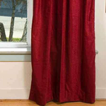 Burgundy velvet grommet top curtains hung at a window