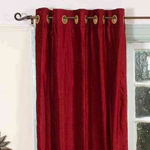 Burgundy velvet grommet top curtains hung at a window
