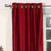 Burgundy velvet grommet top curtains hung at a window